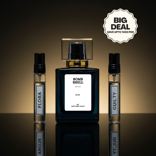 Perfume bottle labeled 'Bomb Shell' with two smaller bottles labeled 'Flora' and 'Guilty' on a reflective surface.